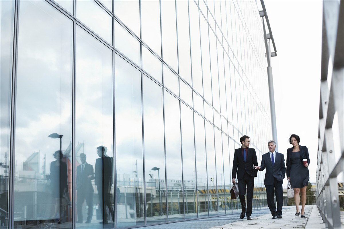 Business People Walking Outside a Building with Glass Windows